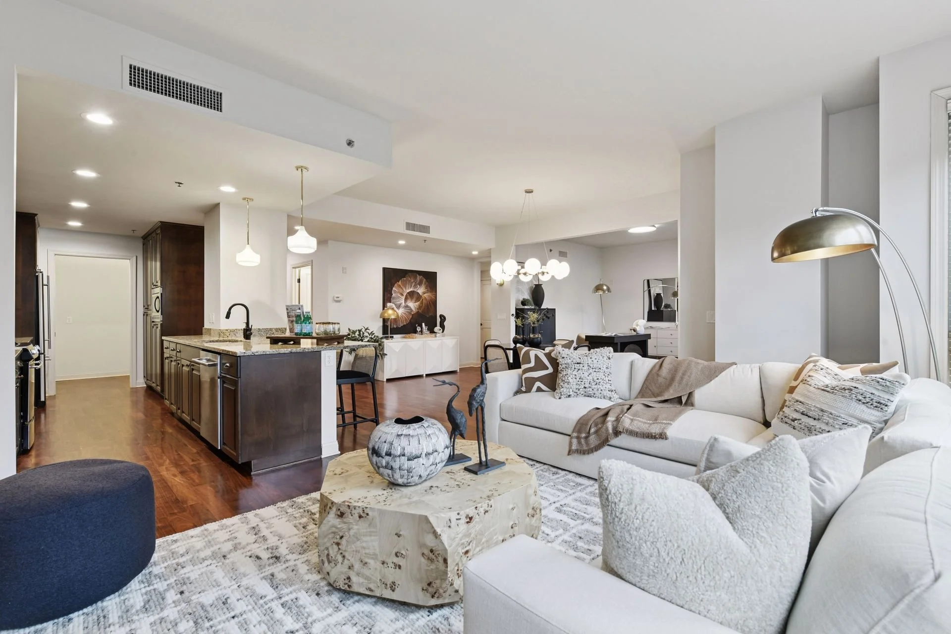 Open-concept living room and kitchen with hardwood floors and a dining area with a chandelier.