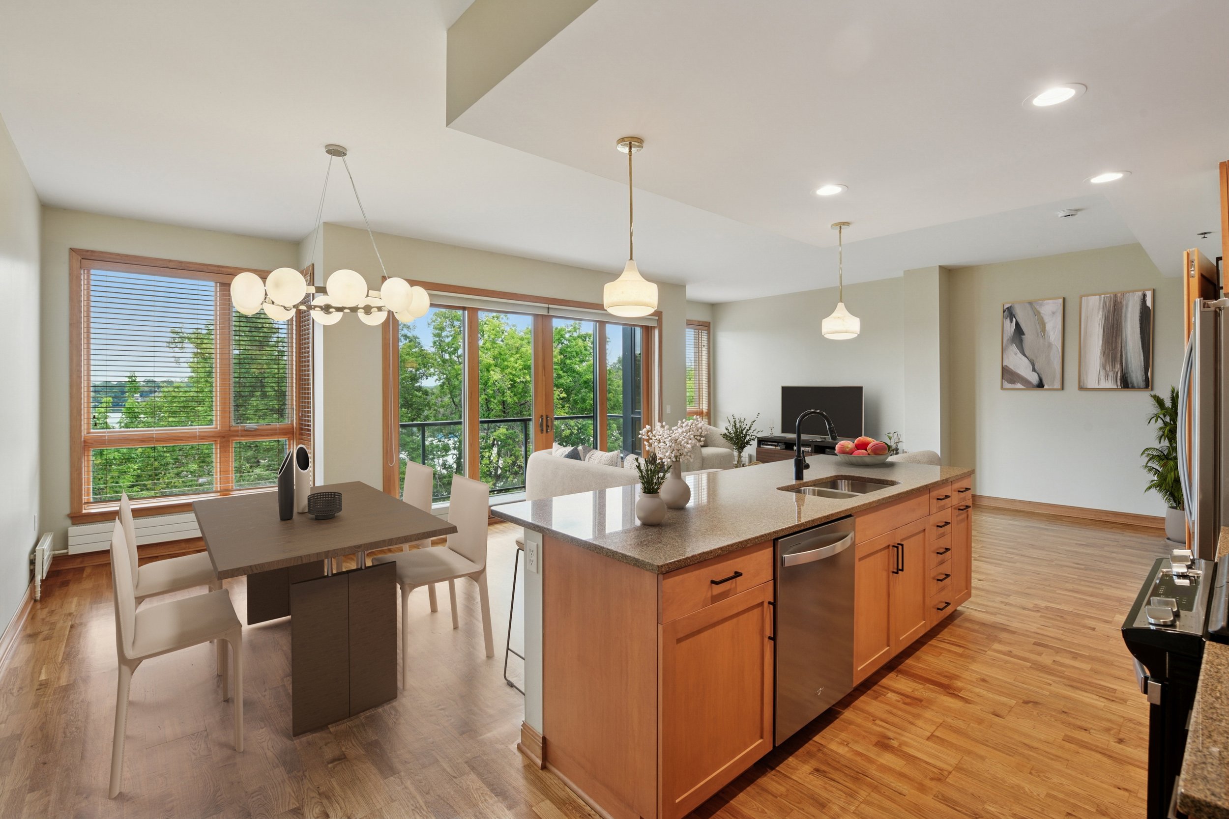 Open-concept living room and kitchen with hardwood floors, large windows, a dining table, and modern decor.