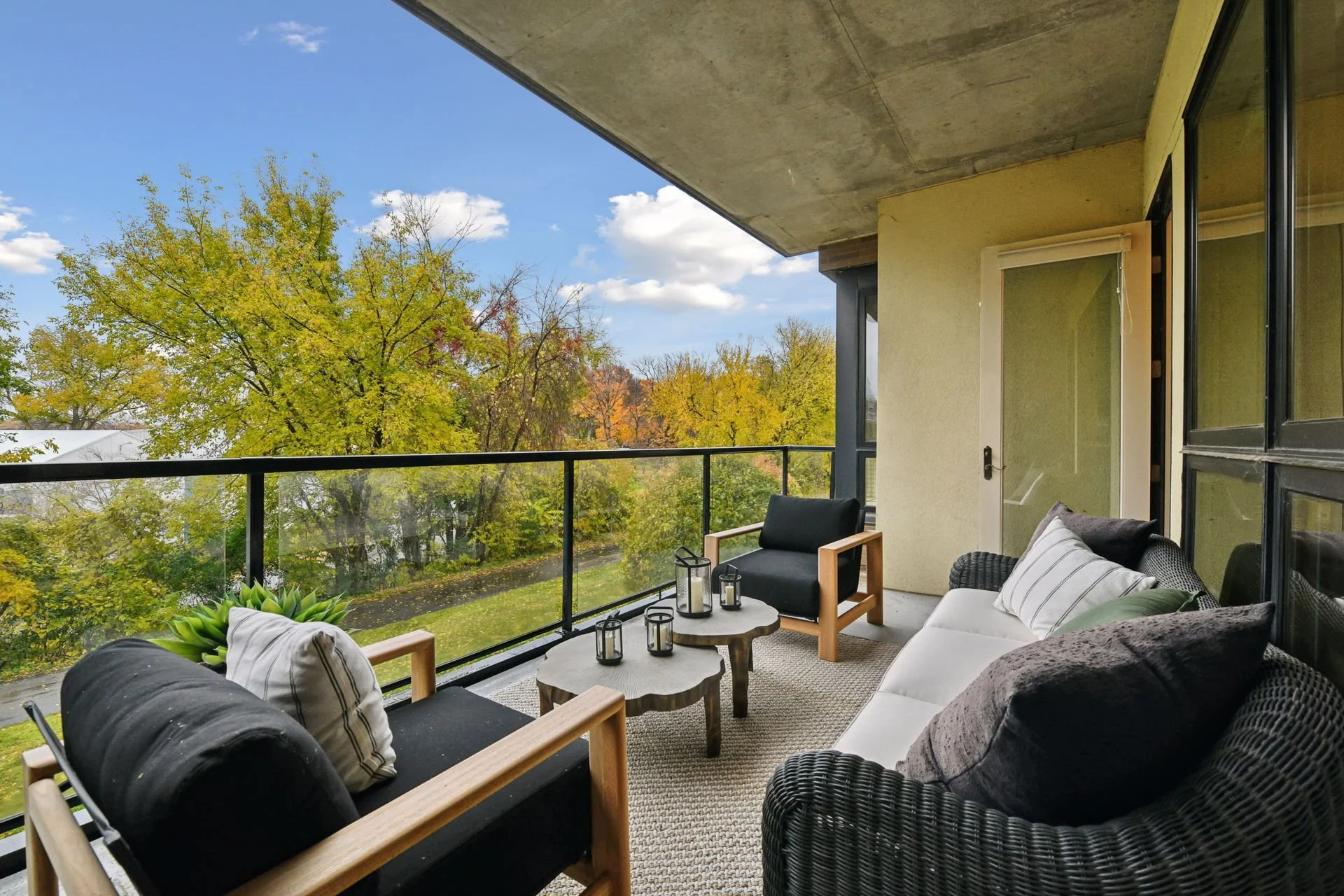 Balcony overlooking trees with fall foliage under a blue sky with clouds.