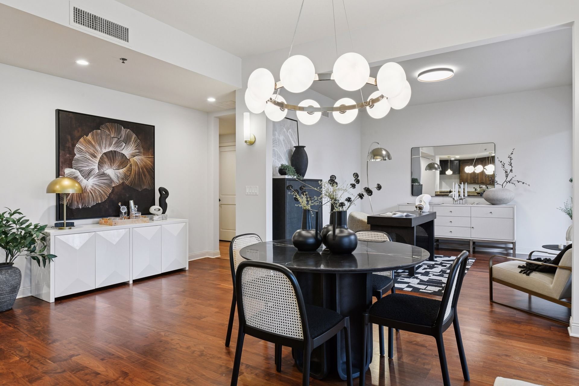 Modern dining and living room with wood floors and contemporary lighting fixtures.
