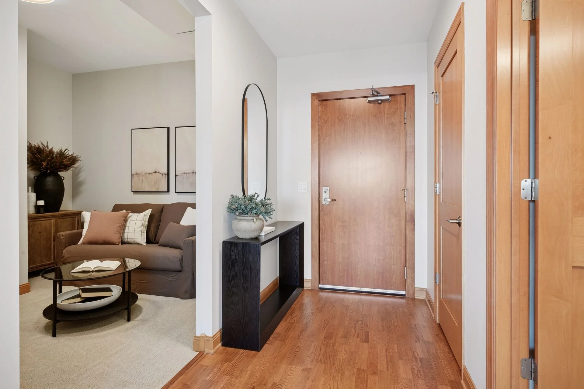 Entryway with a wooden door, and a view into a living room.