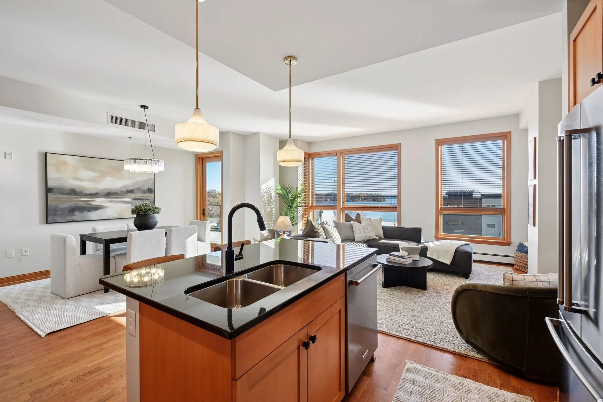 Open-concept living and dining area with large windows, and a kitchen island, overlooking Lake Minnetonka outside.