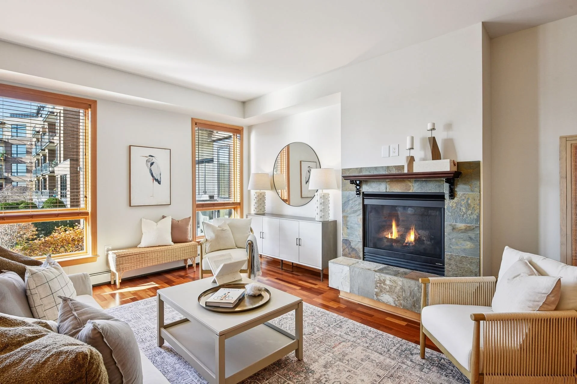 Living room with large windows and a fireplace with stone surround.
