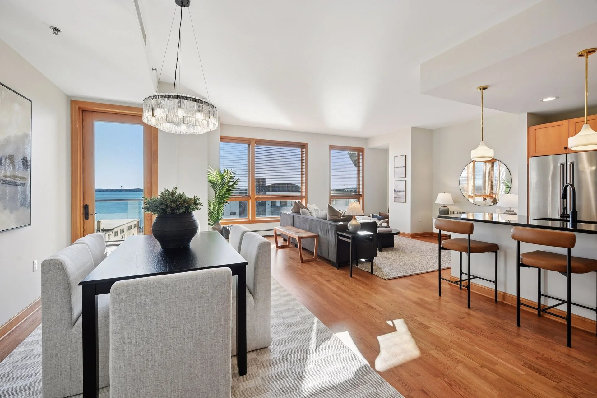 Open-concept living and dining area with large windows, hardwood floors, and a spacious kitchen island.