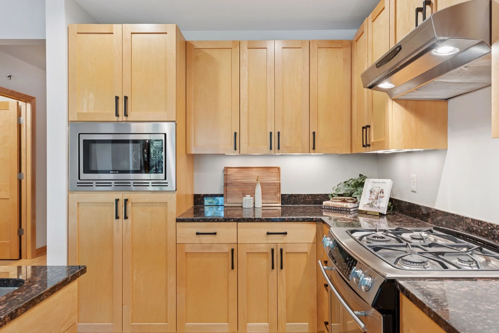 Kitchen with wooden cabinets, black countertops, a gas stove, and a built-in microwave.