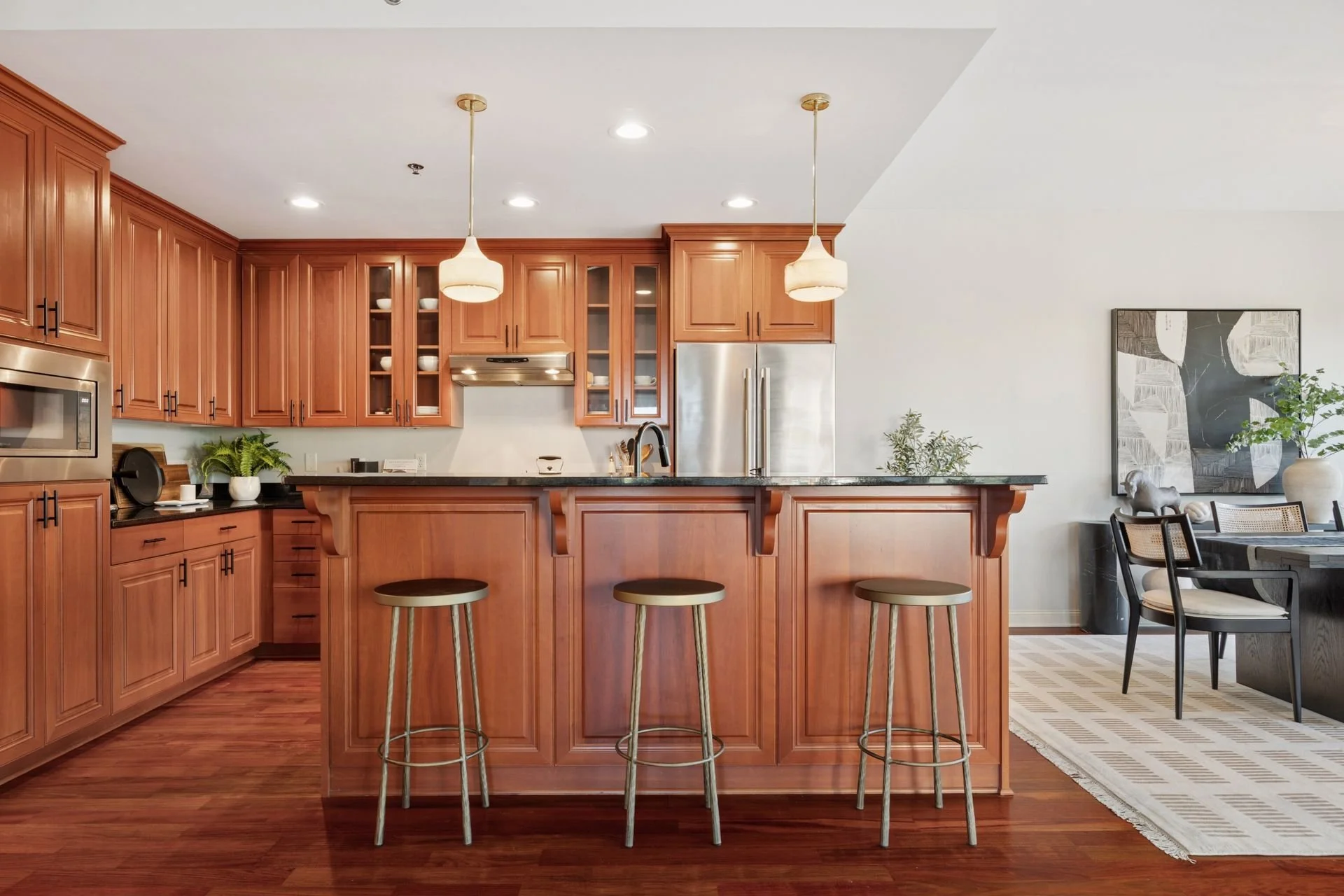 Kitchen with wooden cabinets, black countertops, stainless steel appliances, and a spacious island. 