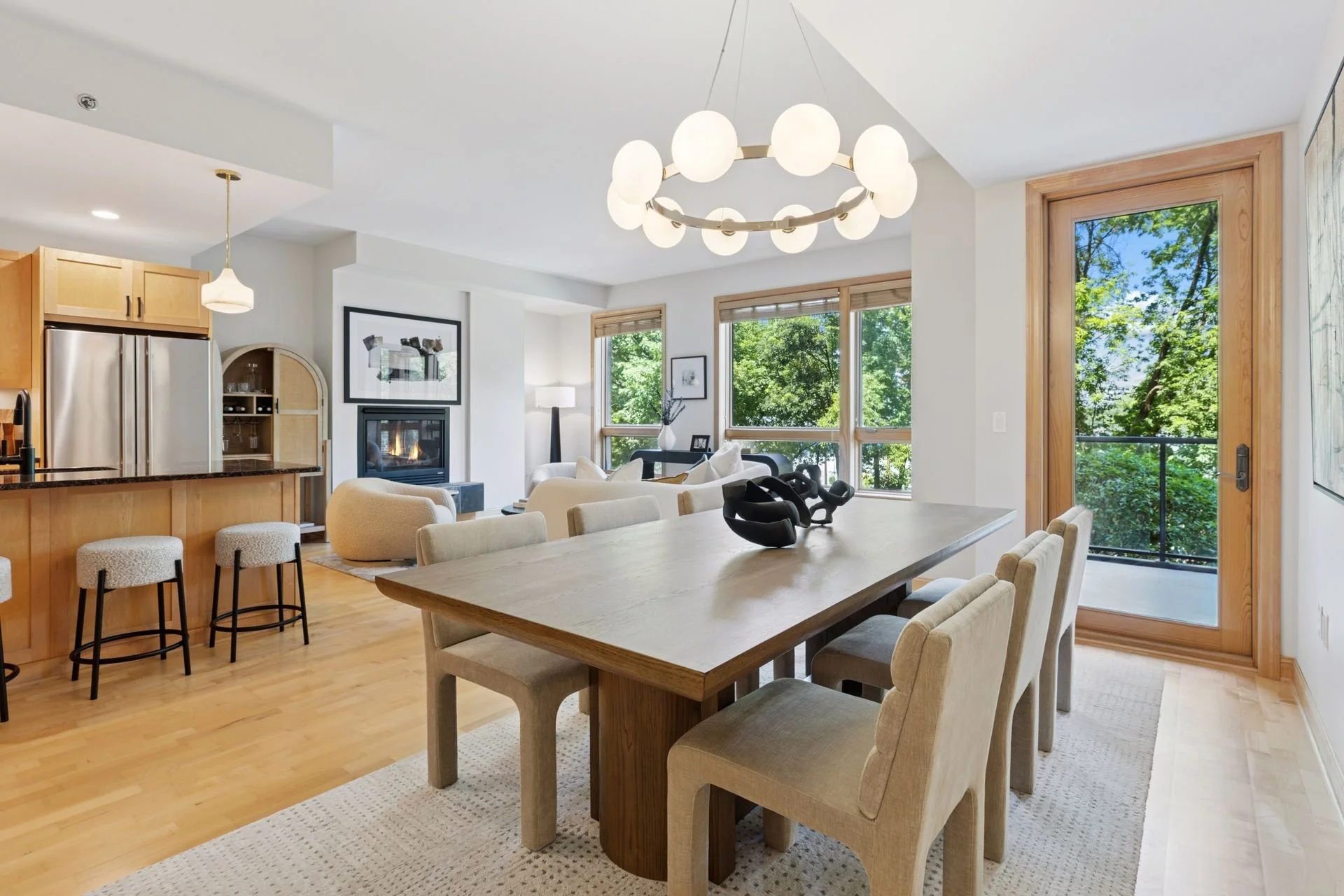 Open plan living and dining area with large windows, wooden accents, and modern lighting fixtures.