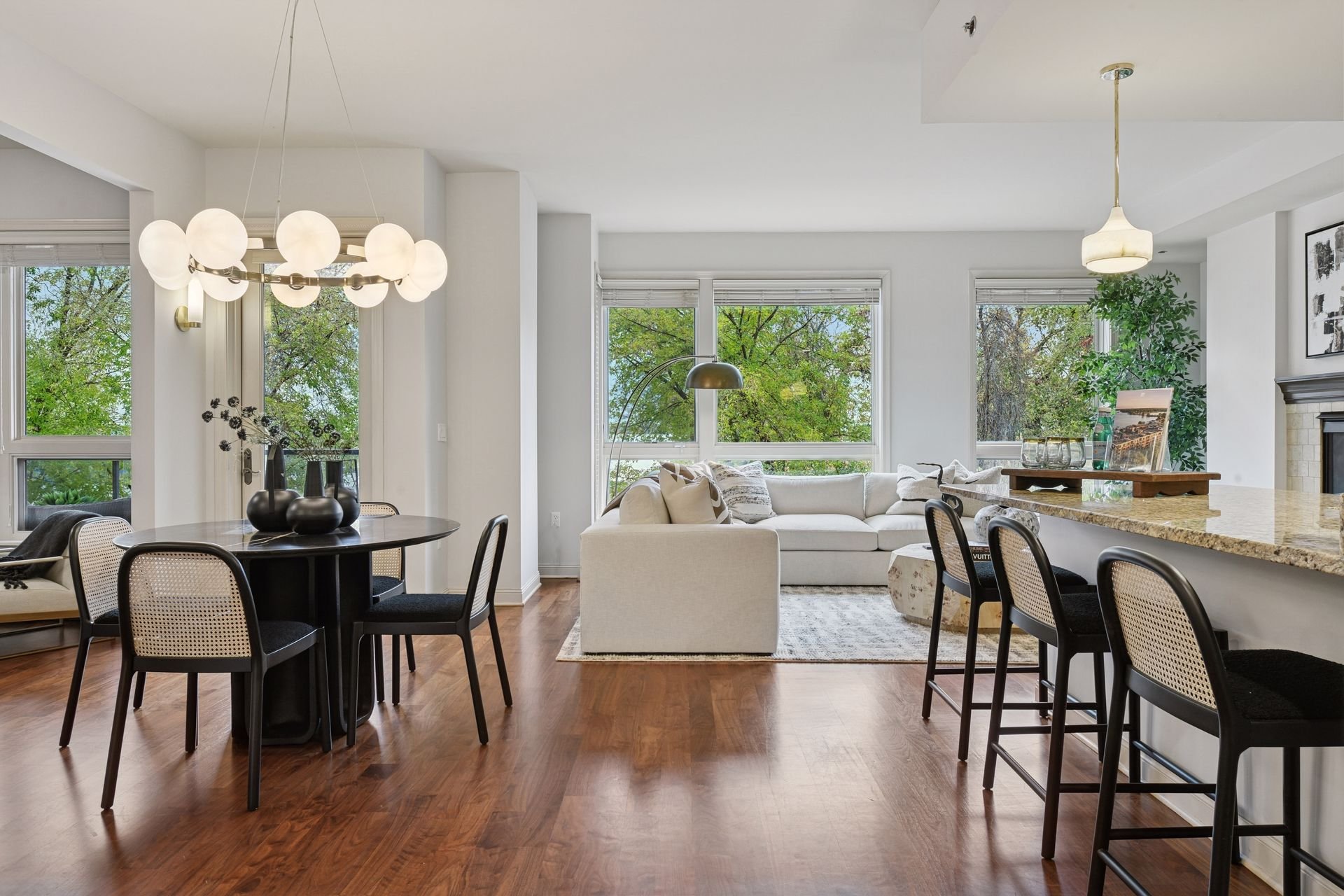 Open-concept living and dining area with hardwood floors and large windows. 