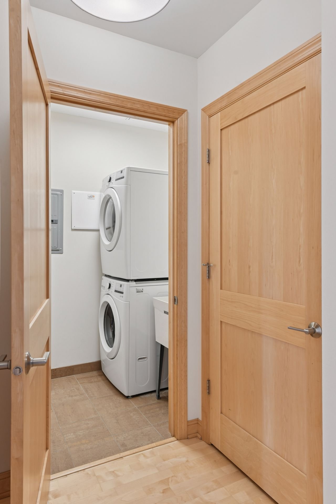 Laundry room with stacked washer and dryer, with a utility sink visible.