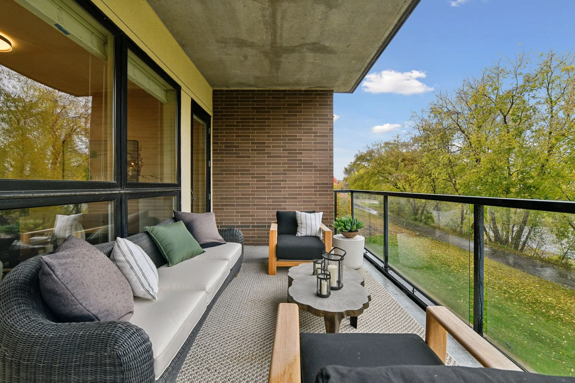 Balcony with a view of green trees and a street, under a partly cloudy sky.