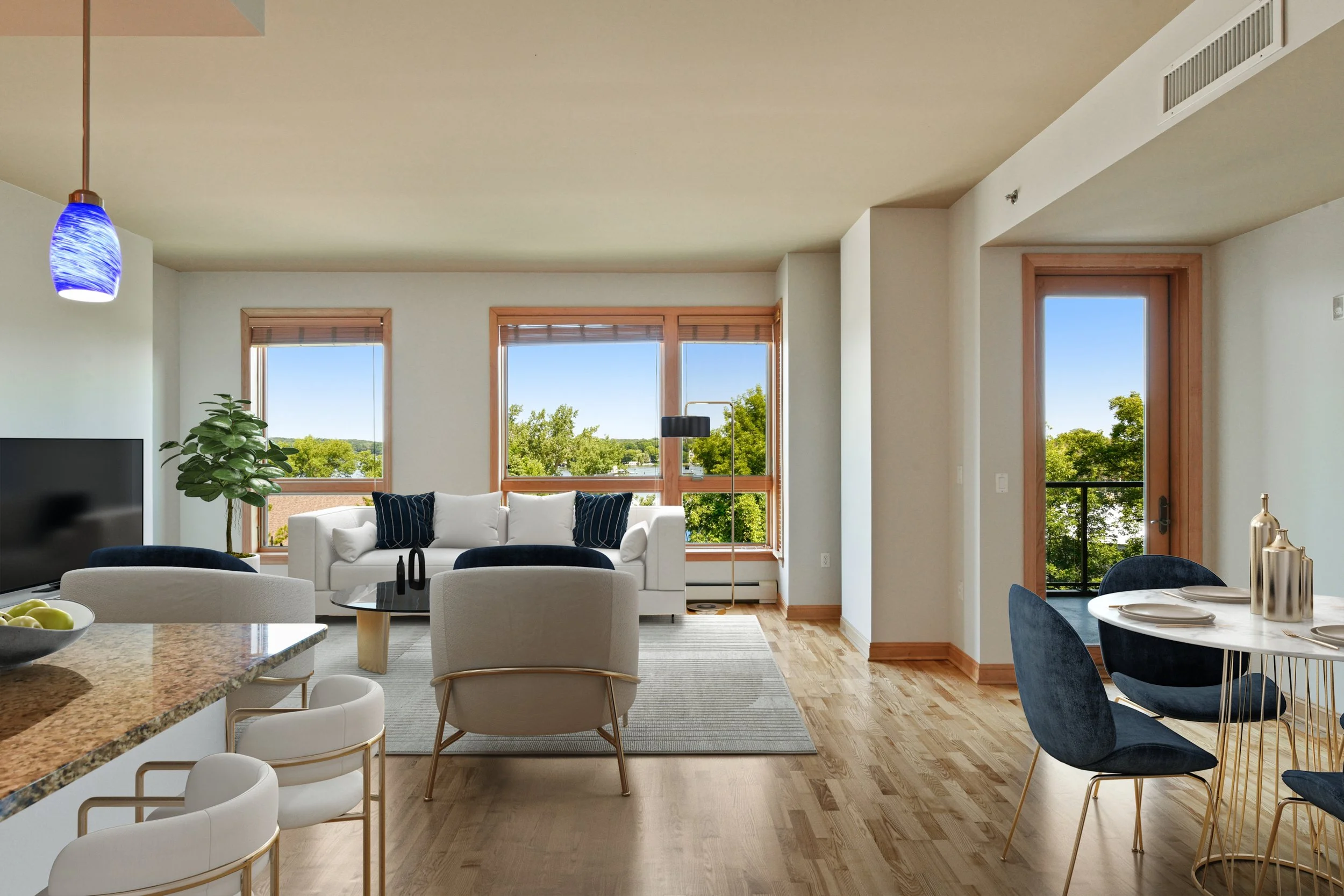 Living room with large windows overlooking green trees, and hardwood floors.