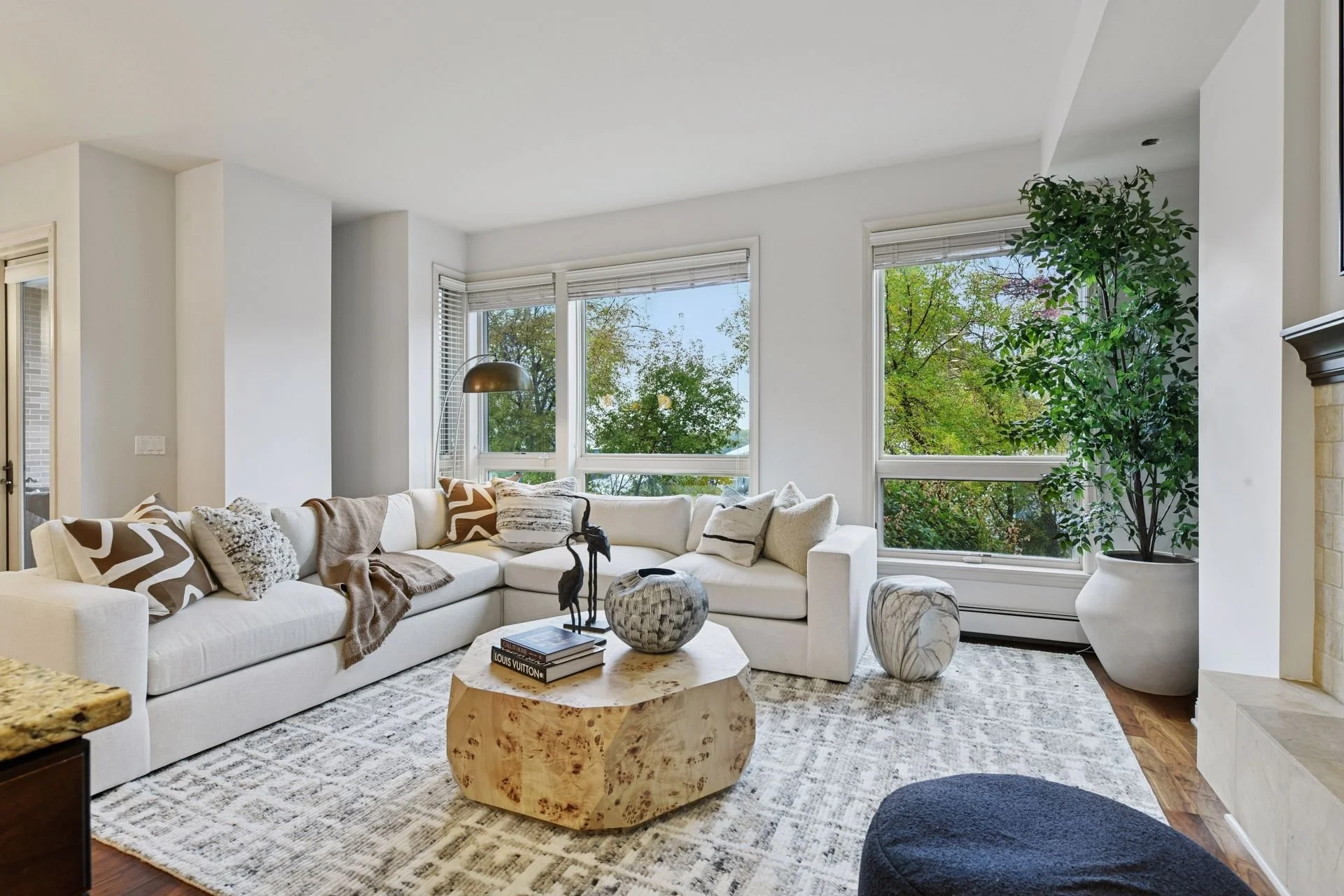 Bright living room with large windows showing greenery outside.
