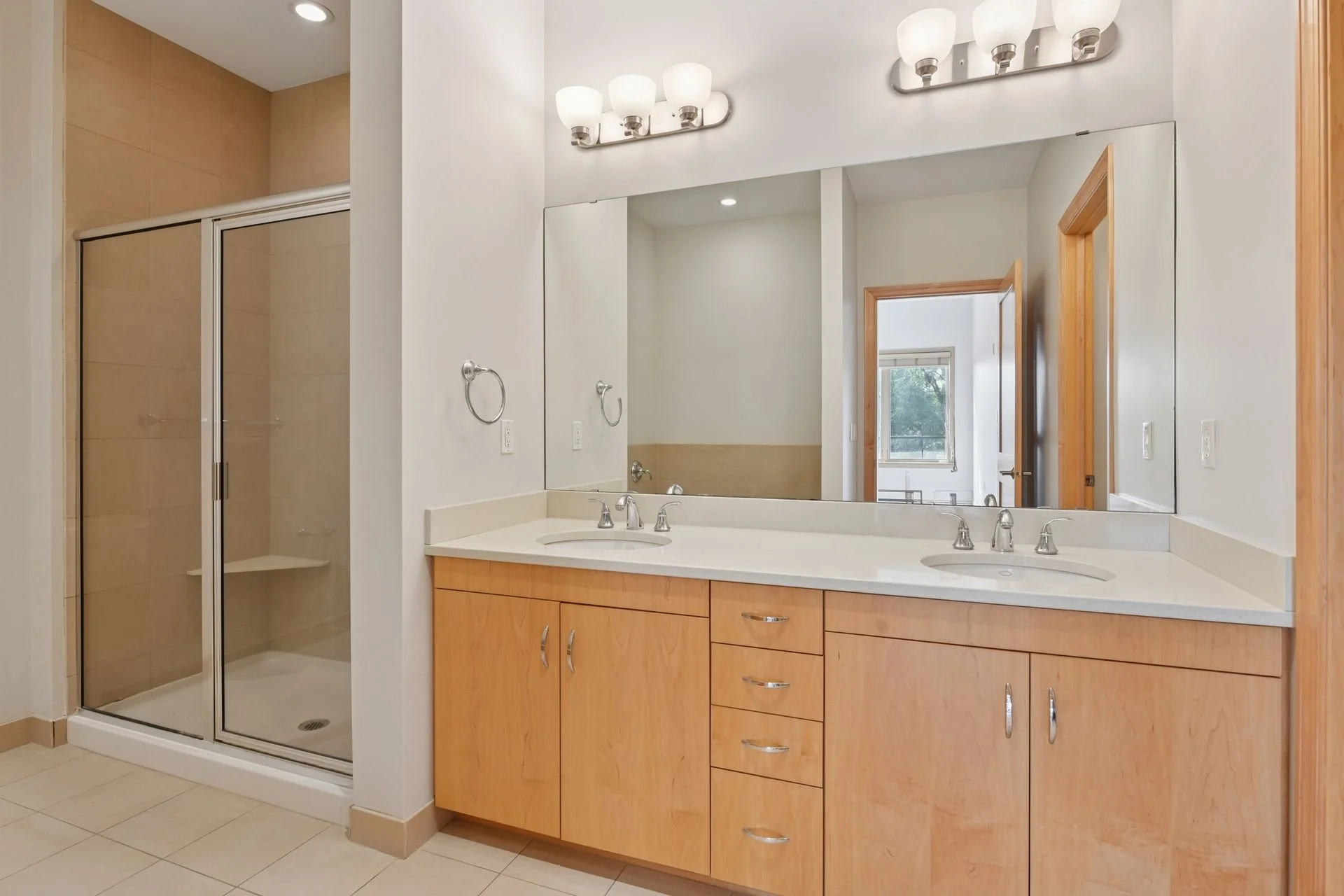 Bathroom with a double sink vanity, large mirror, and a shower with a glass door.