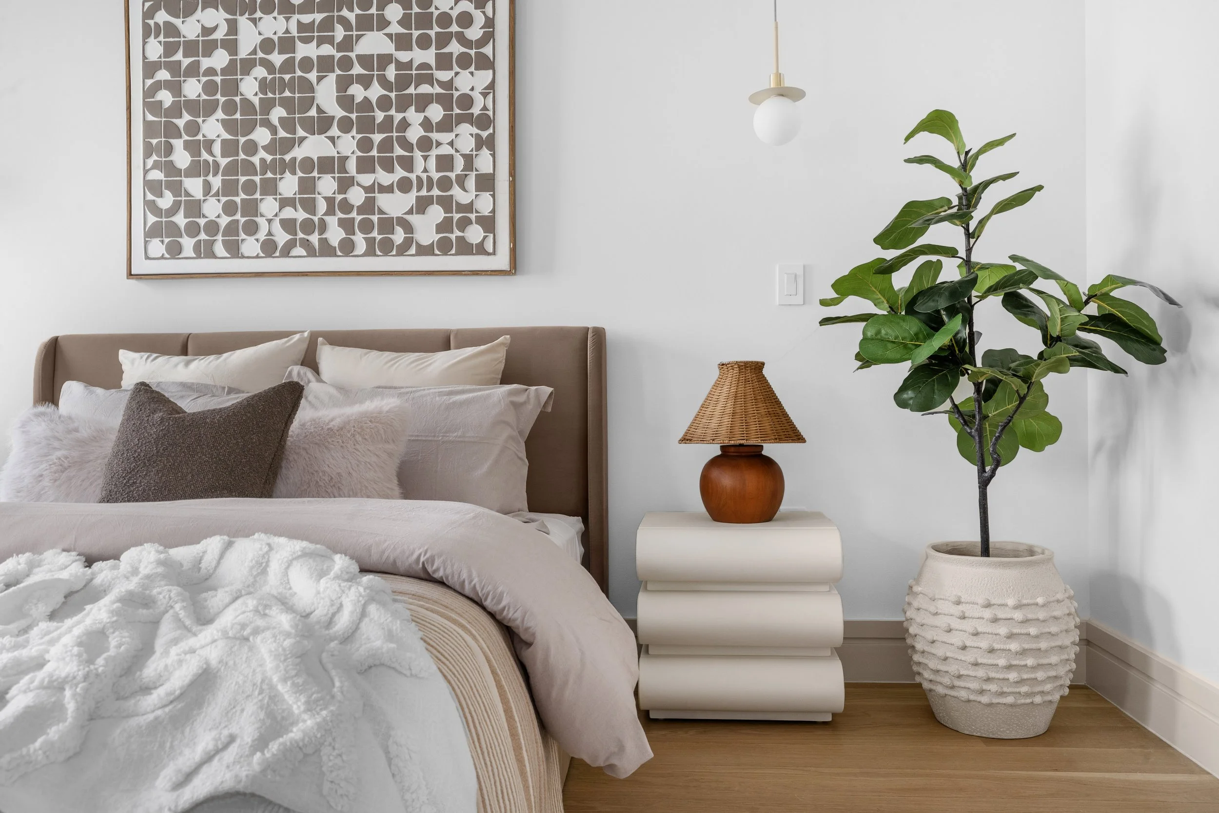 master bedroom furniture details featuring potted plant and bedside table with rattan lamp