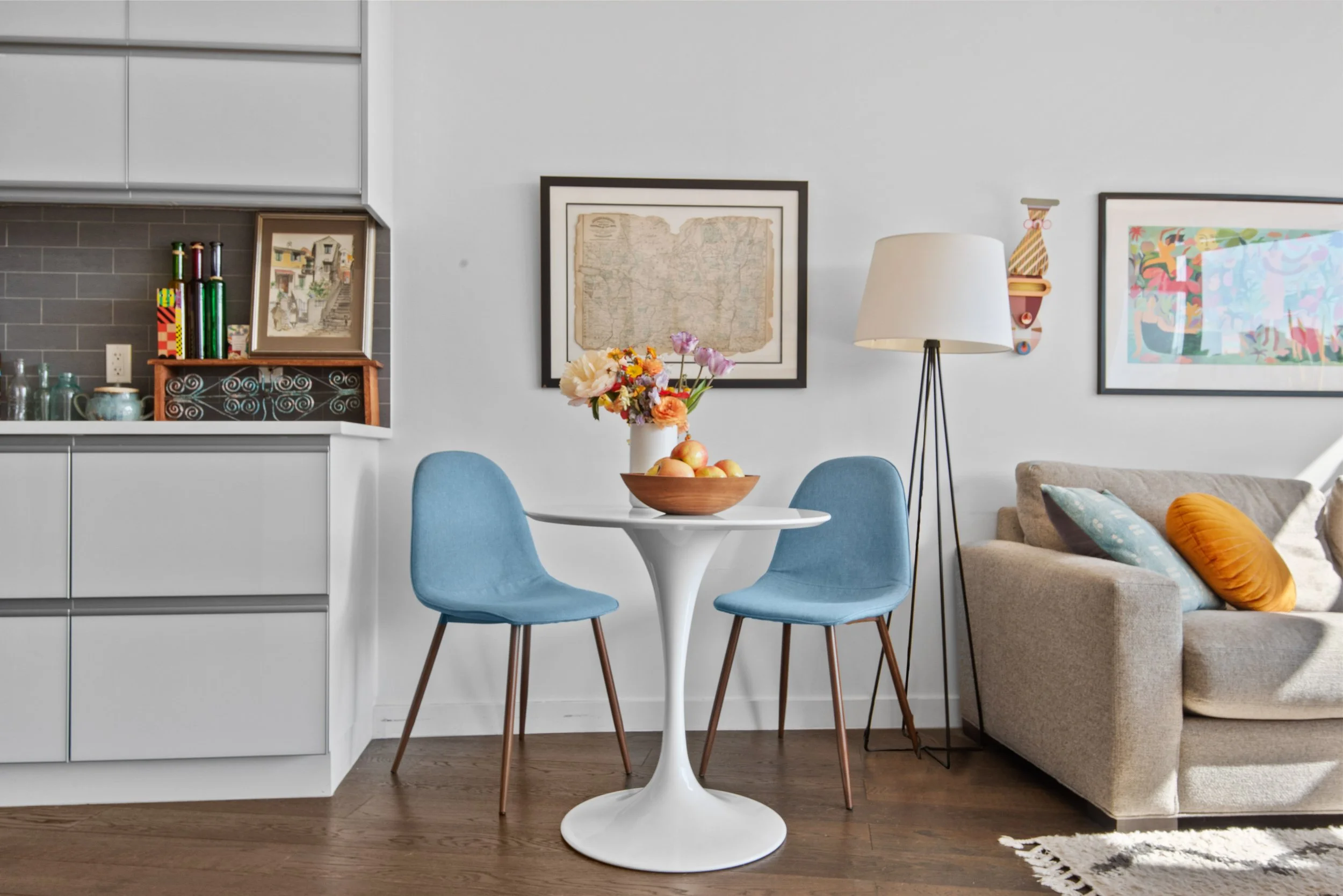 intimate nyc apartment dining area with light blue chairs and fruit bowl