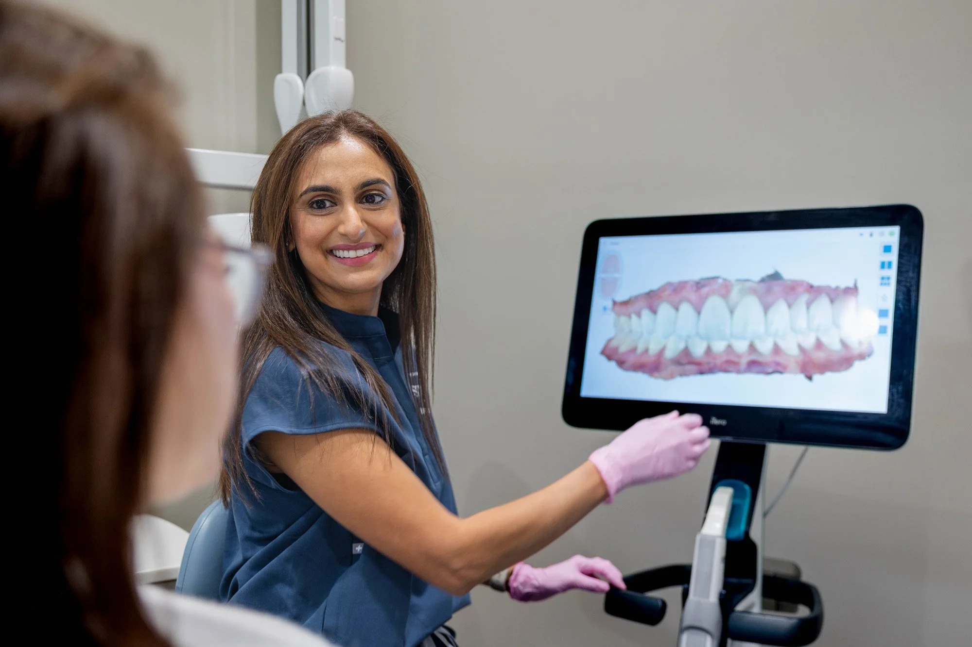 Dental professional showing a digital image of teeth on a monitor to a patient in a dental office.