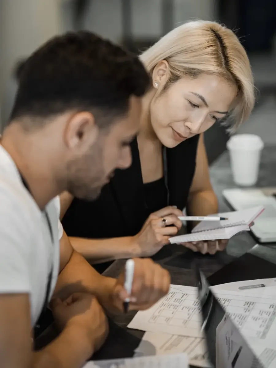 Two people leaning over a table reviewing documents