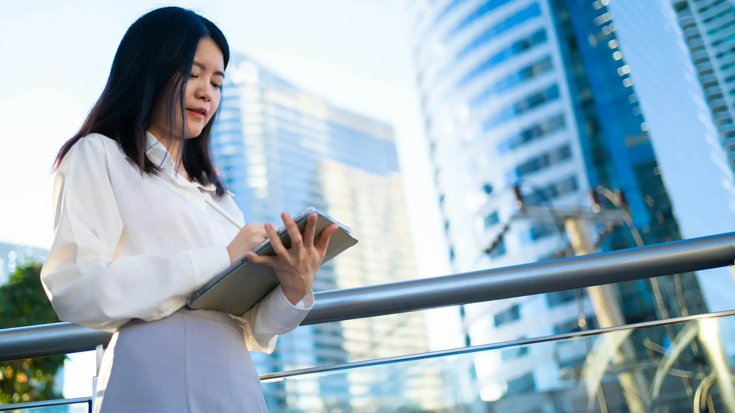 Person in business clothes outside, writing in a notebook