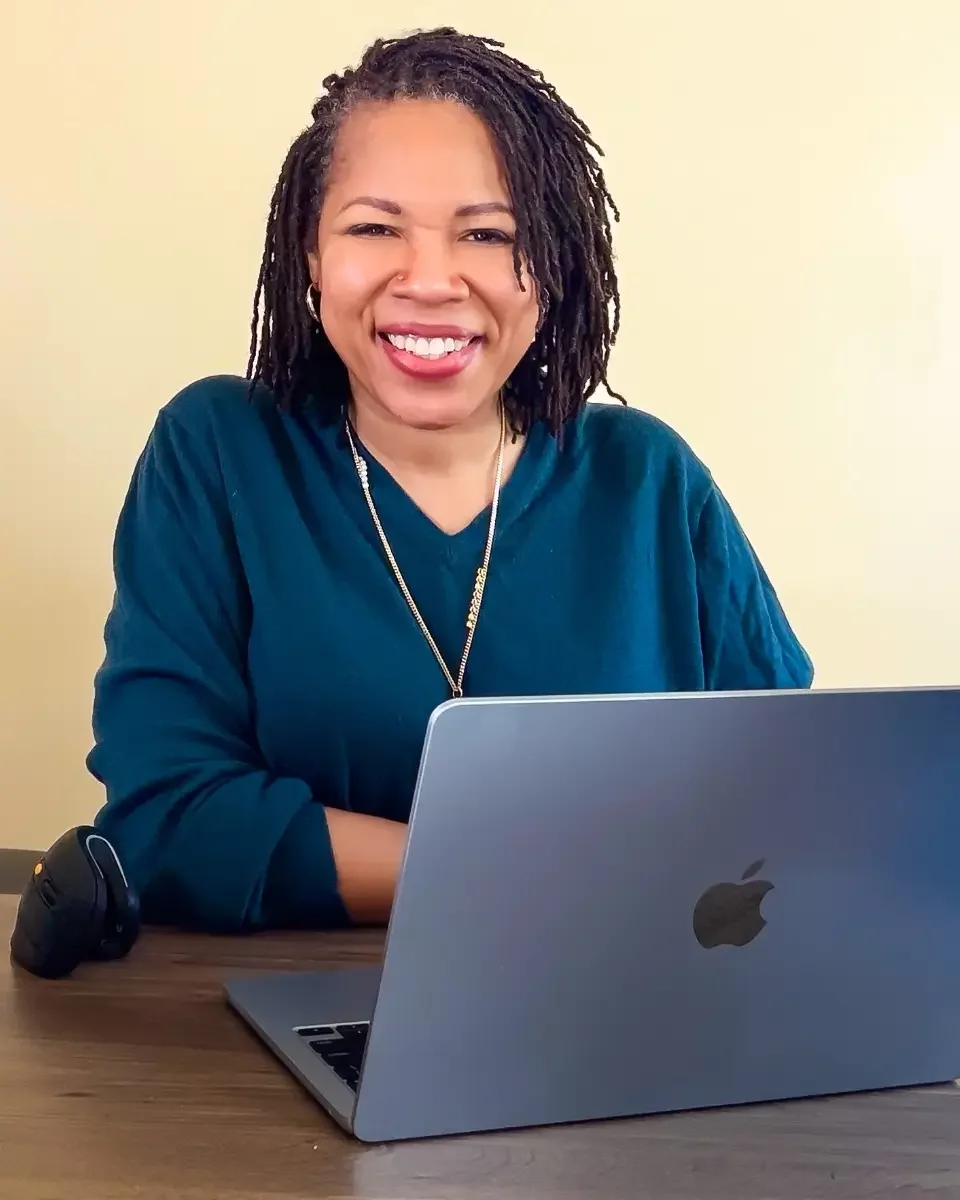 Katherine sitting at her desk with her laptop smiling