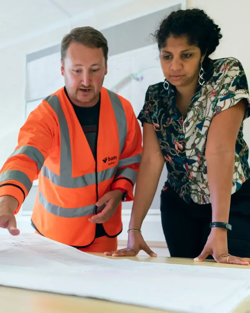 Two people leaning over a table reviewing plans