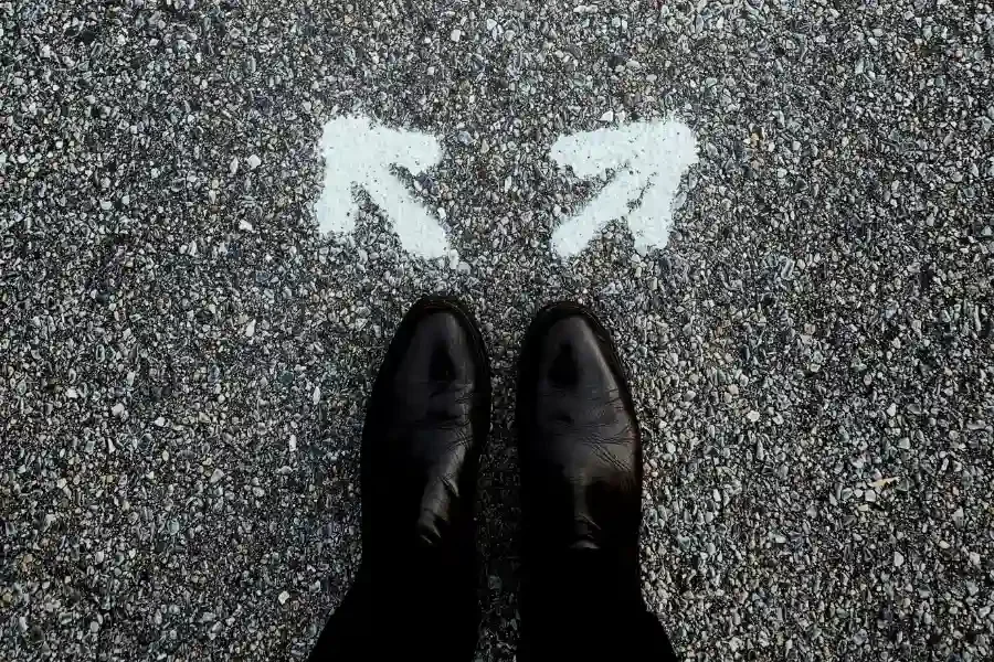 Person standing on a road between two directional arrows