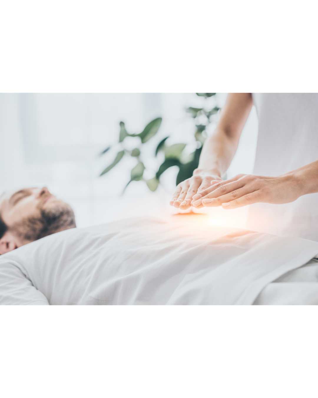 A person receiving an energy healing or Reiki session on their stomach while lying on a bed, with their eyes closed.