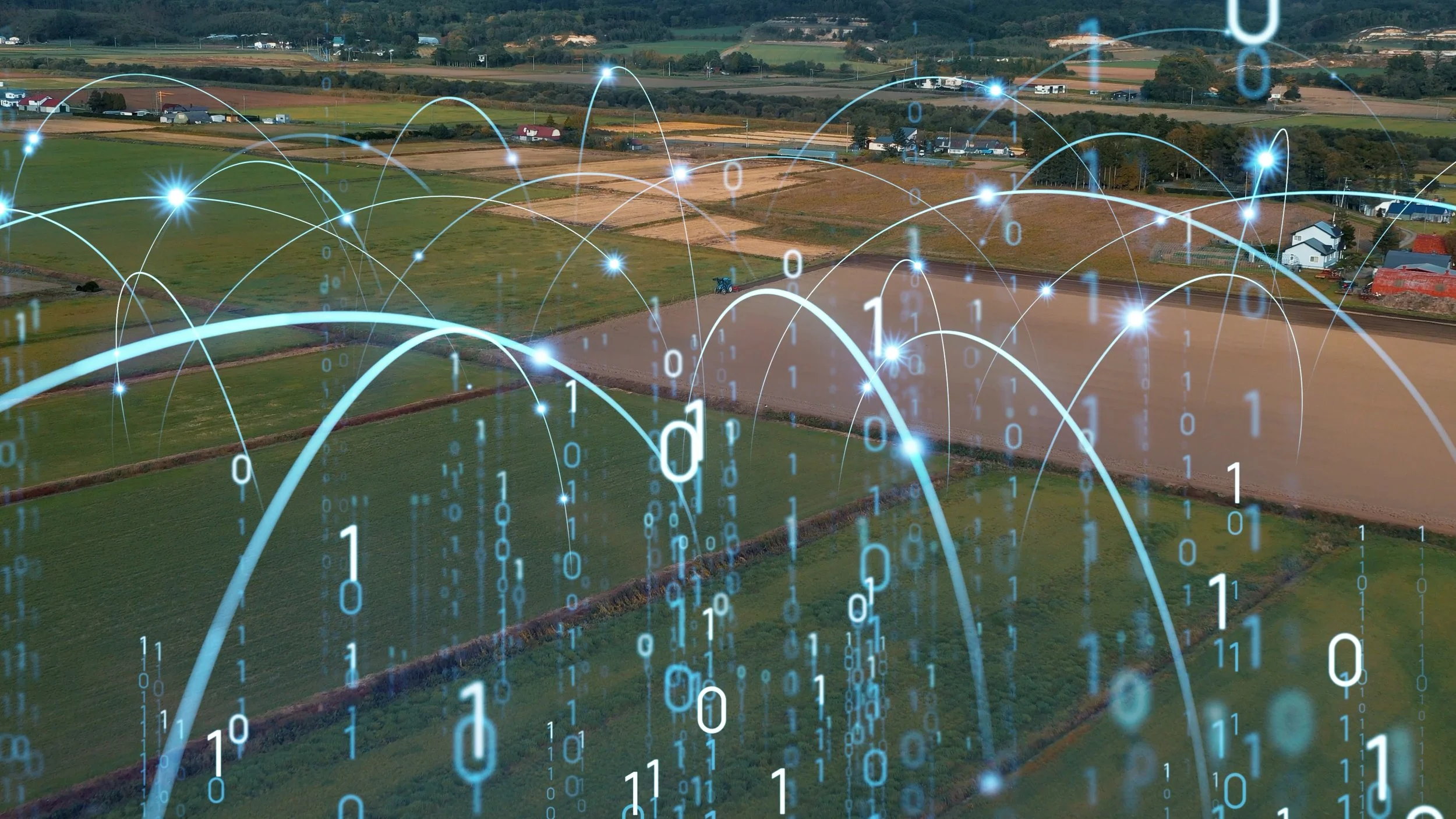 A rural landscape with fields and scattered houses overlaid with digital binary code and glowing digital lines representing a data network.