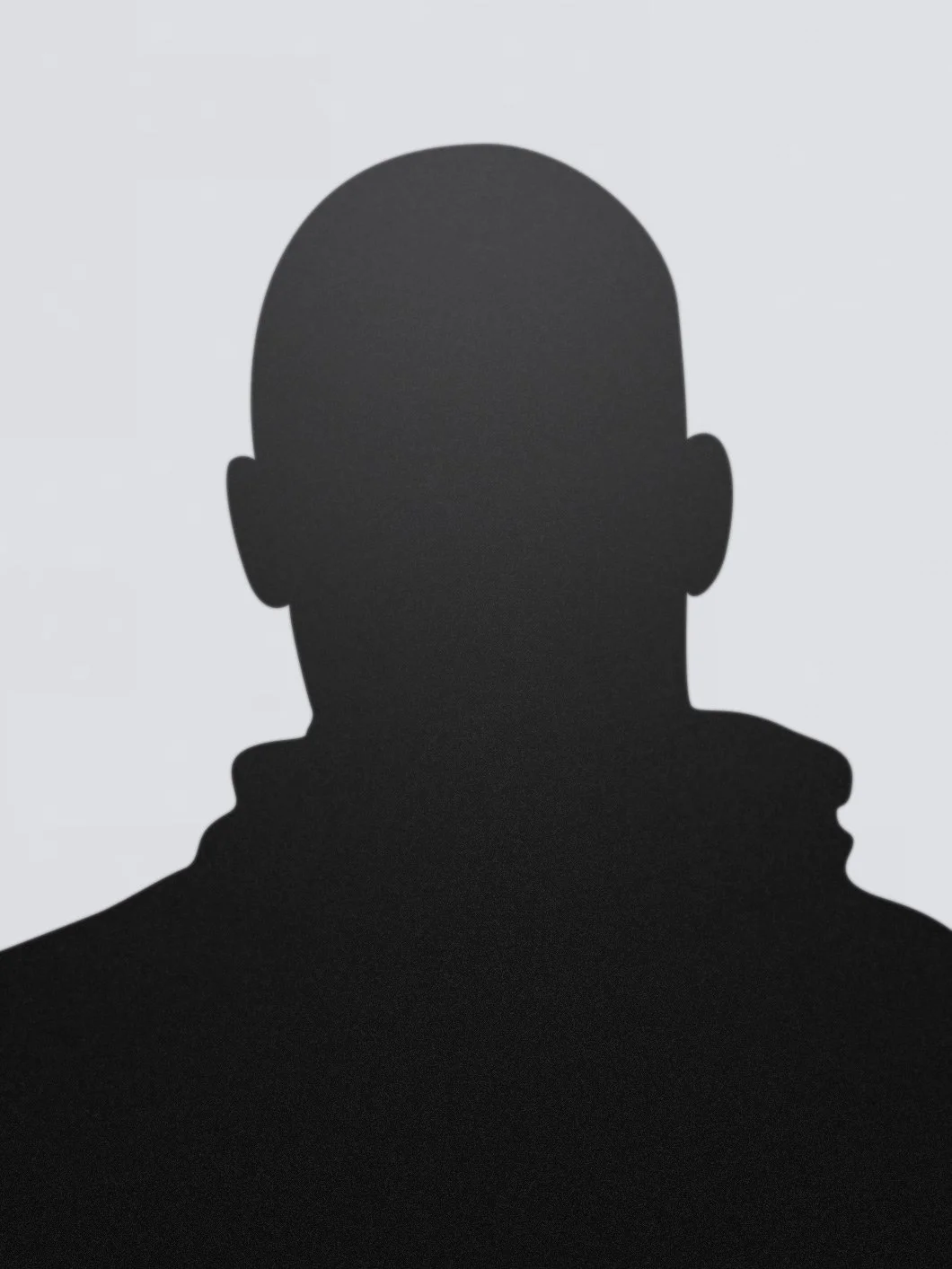 Silhouette of a person with a bald head and visible ear against a light background.
