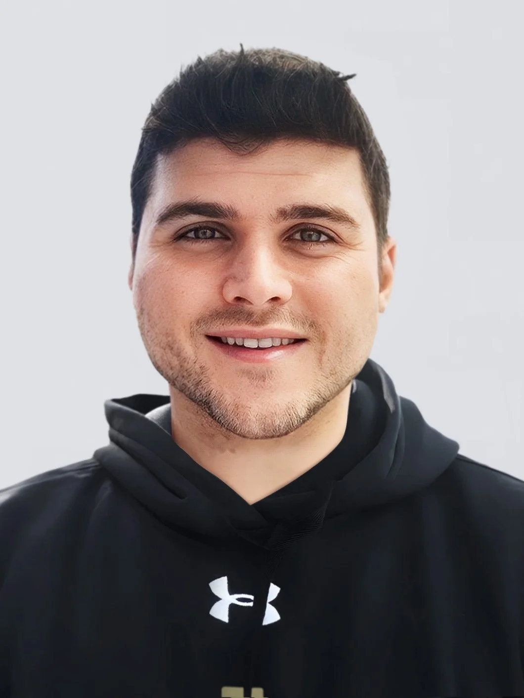 A man smiling, wearing a black Under Armour hoodie.