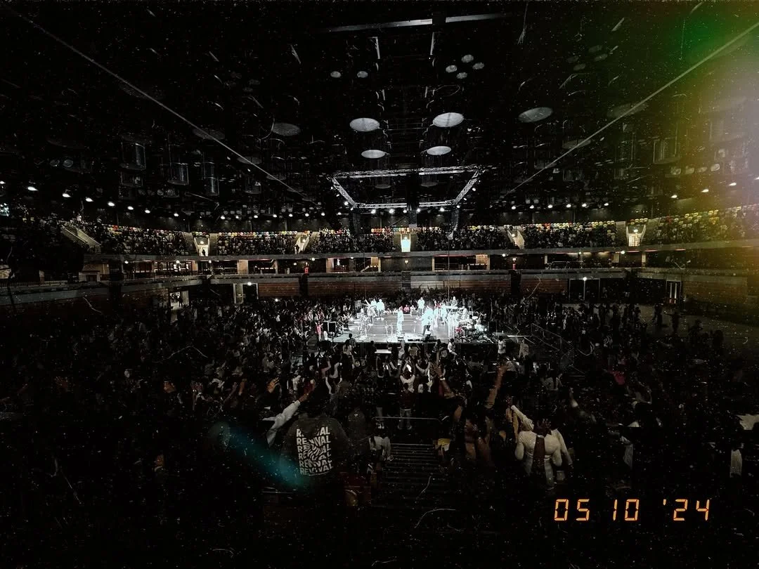Crowd attending a live concert or event in a large indoor arena with stage lights focused on the performers.