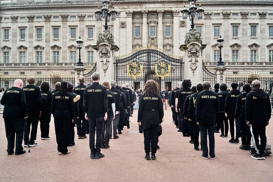 Group of people in black clothing standing in front of Buckingham Palace in London, England.