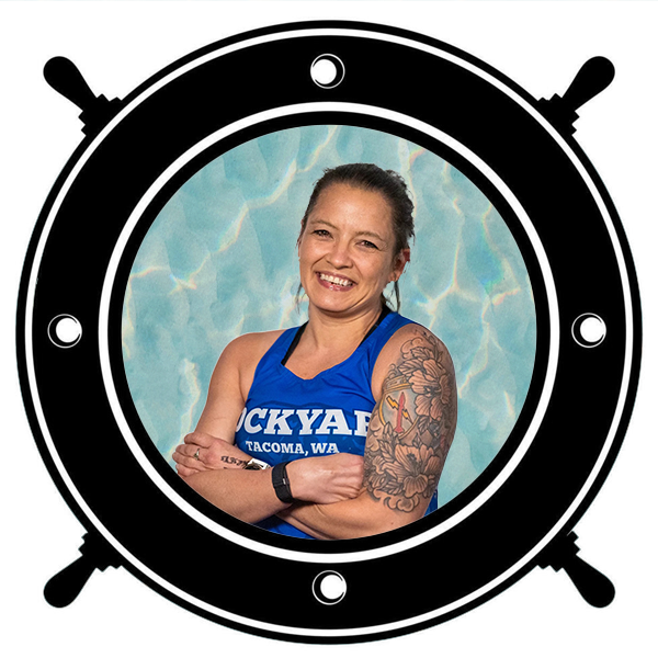 Portrait of a smiling woman with tattoos on her arm, winking and looking back, seen through a circular porthole.