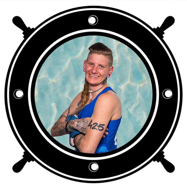Person smiling, holding a blue helmet, wearing a white and blue sports jersey seen through a circular porthole. 