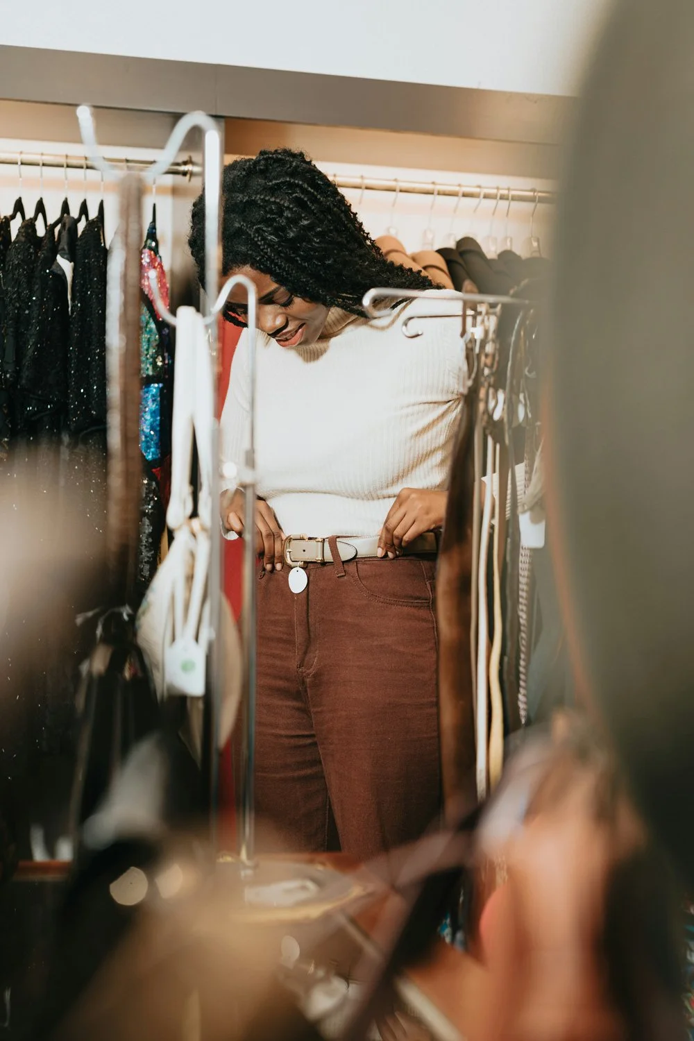 A woman shopping for clothes, browsing through a rack filled with various garments in a store.