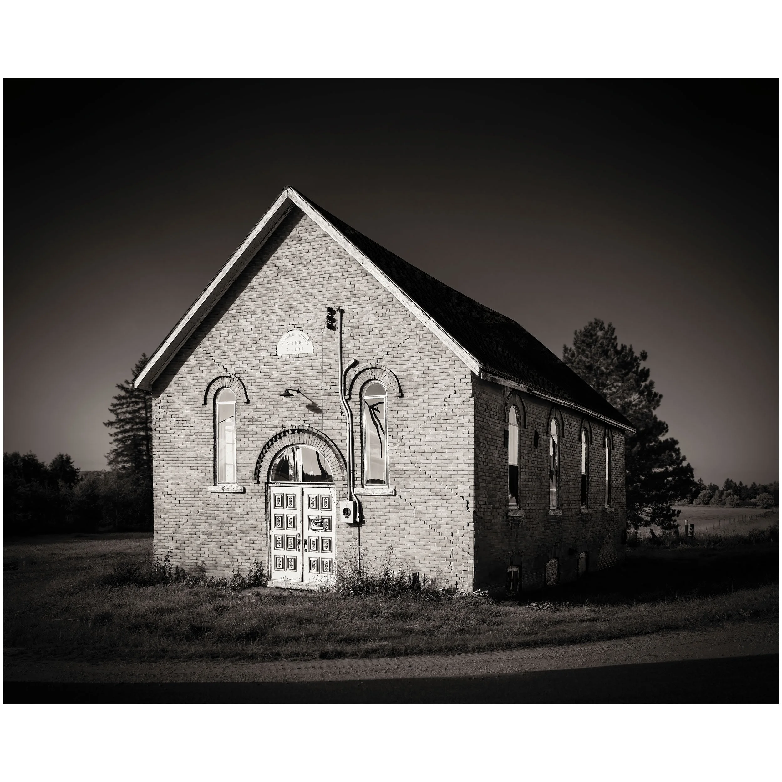 A black and white photo of a church with a pointed roof and brick walls, black shutters, arched windows, and a sign that reads "Hoper Church".