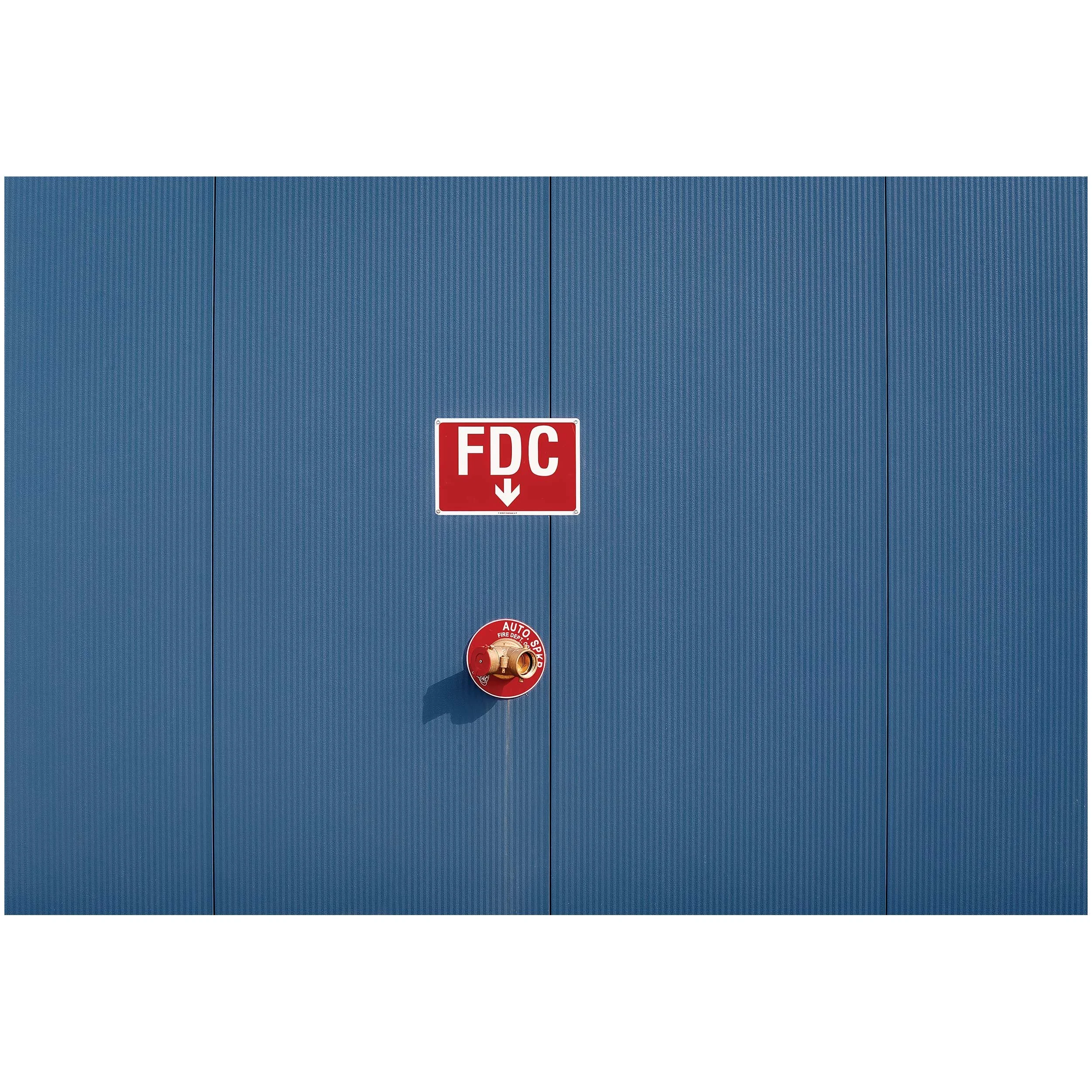 Blue metal privacy fence with a red and white 'FDC' fire department access sign and an additional red circular security sign.