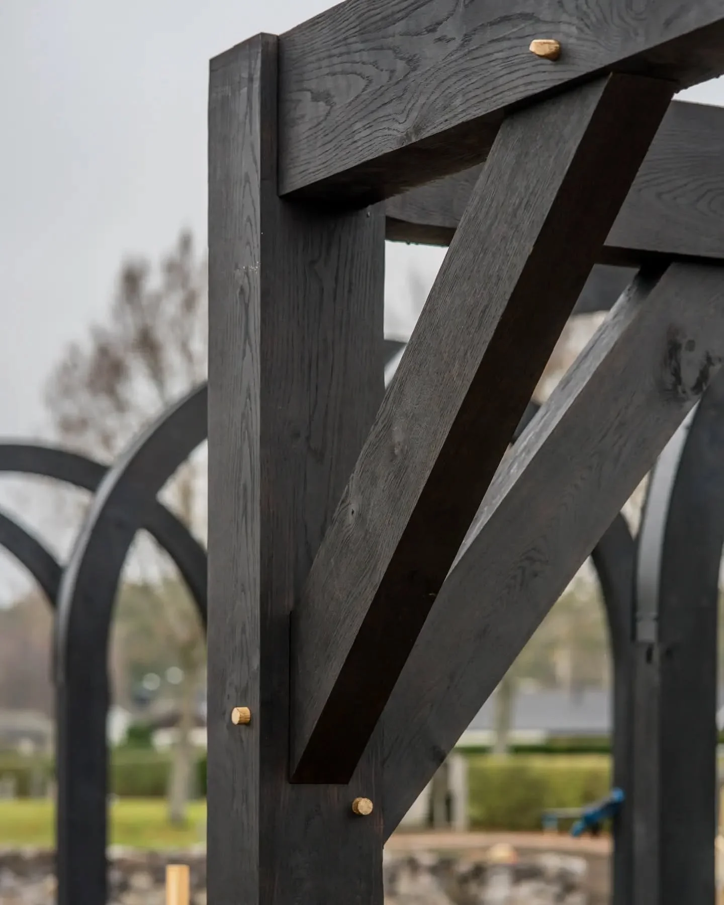 Close-up of a black wooden park bench with metal arches in the background.