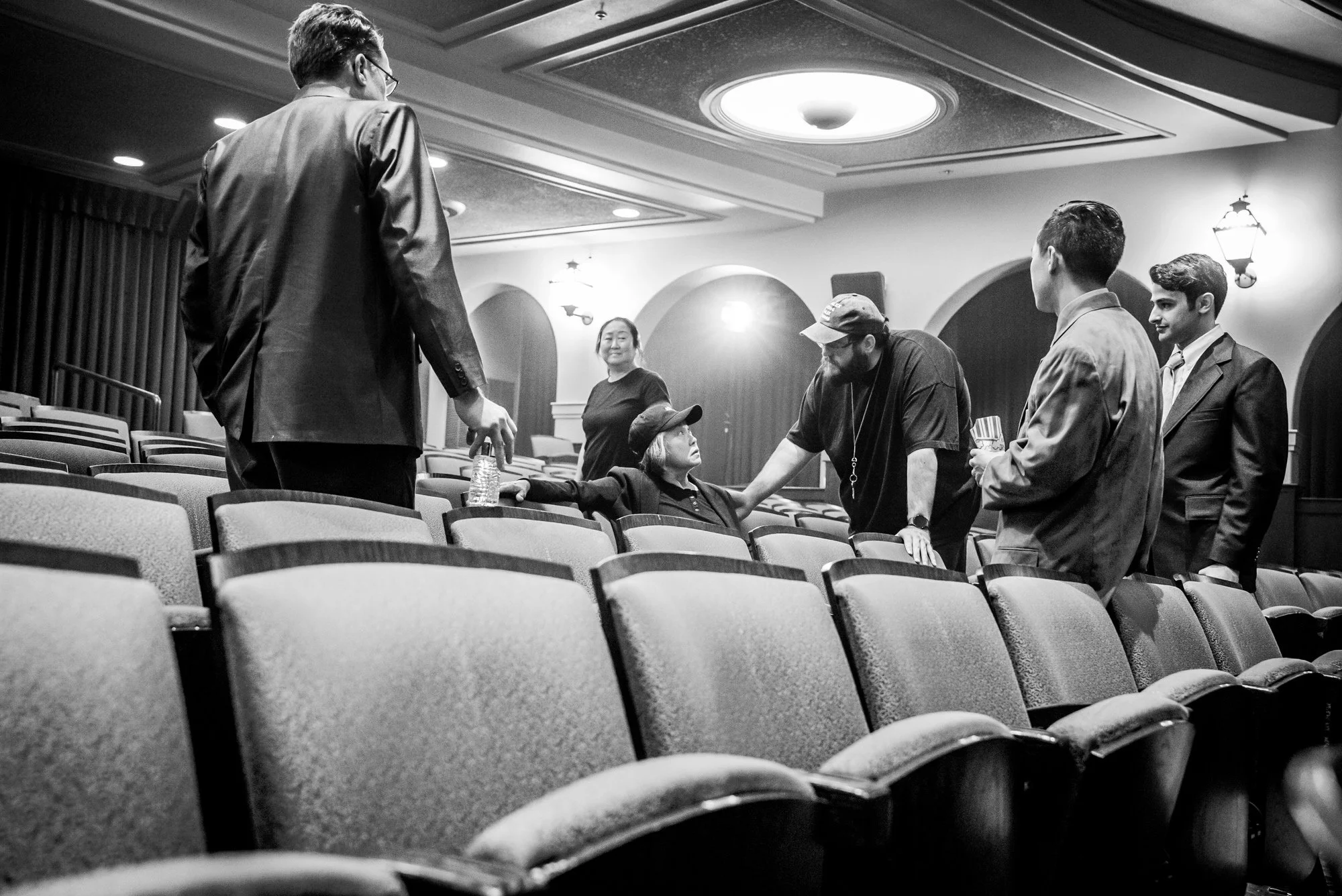 Cast and crew confer with their director while filming theater scenes.