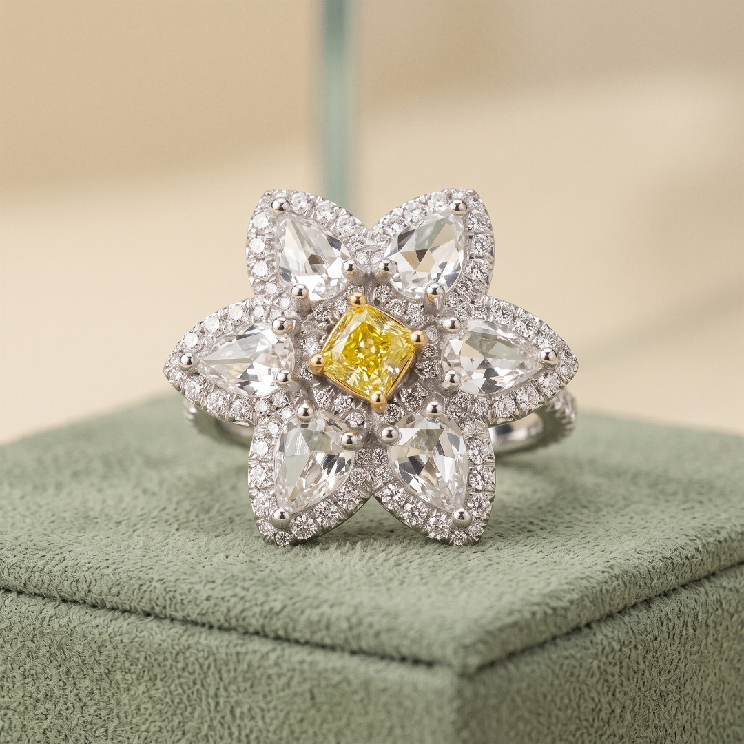 A flower-shaped diamond ring with a yellow center stone, surrounded by multiple smaller diamonds, displayed on a green surface.