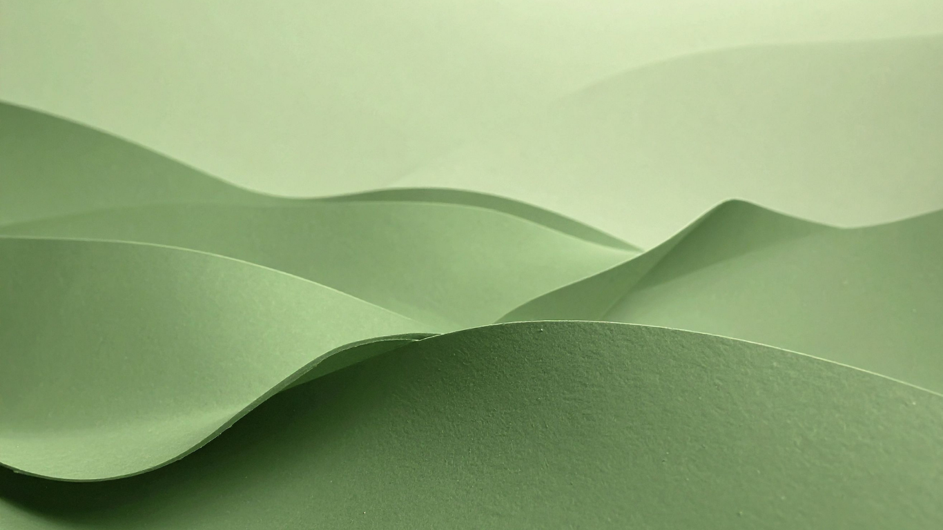Close-up of layered green paper with gentle curves and varying shades of green.