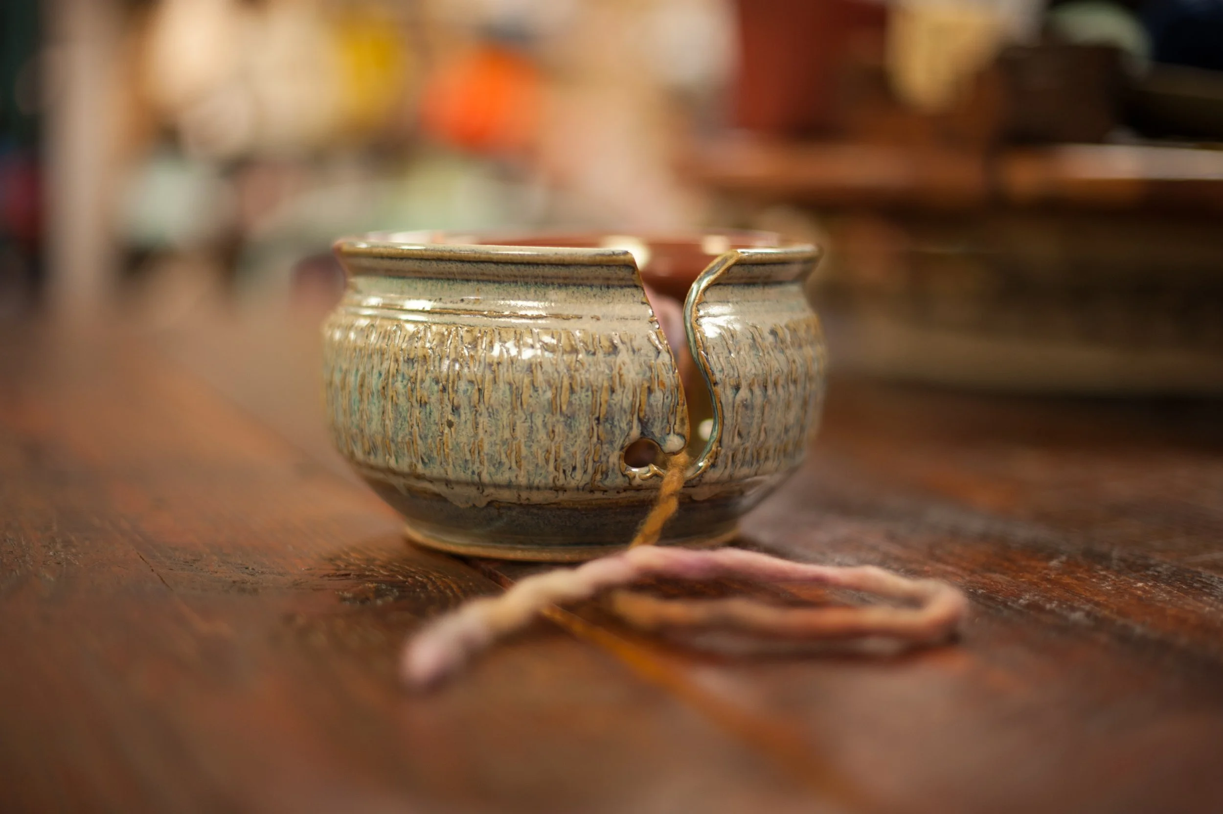 A ceramic yarn holder bowl on a wooden surface.