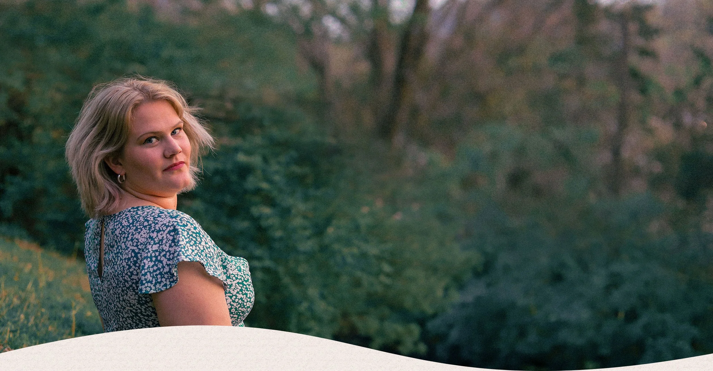 Natalie Uhlenhake sitting on a hill in a floral dress