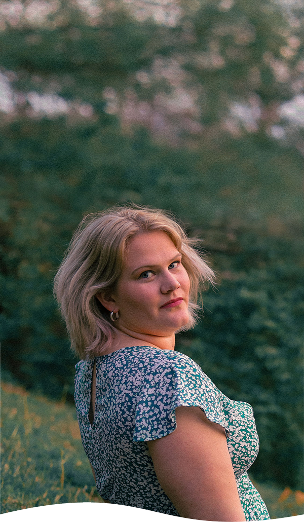 Natalie Uhlenhake sitting on a hill in a floral dress