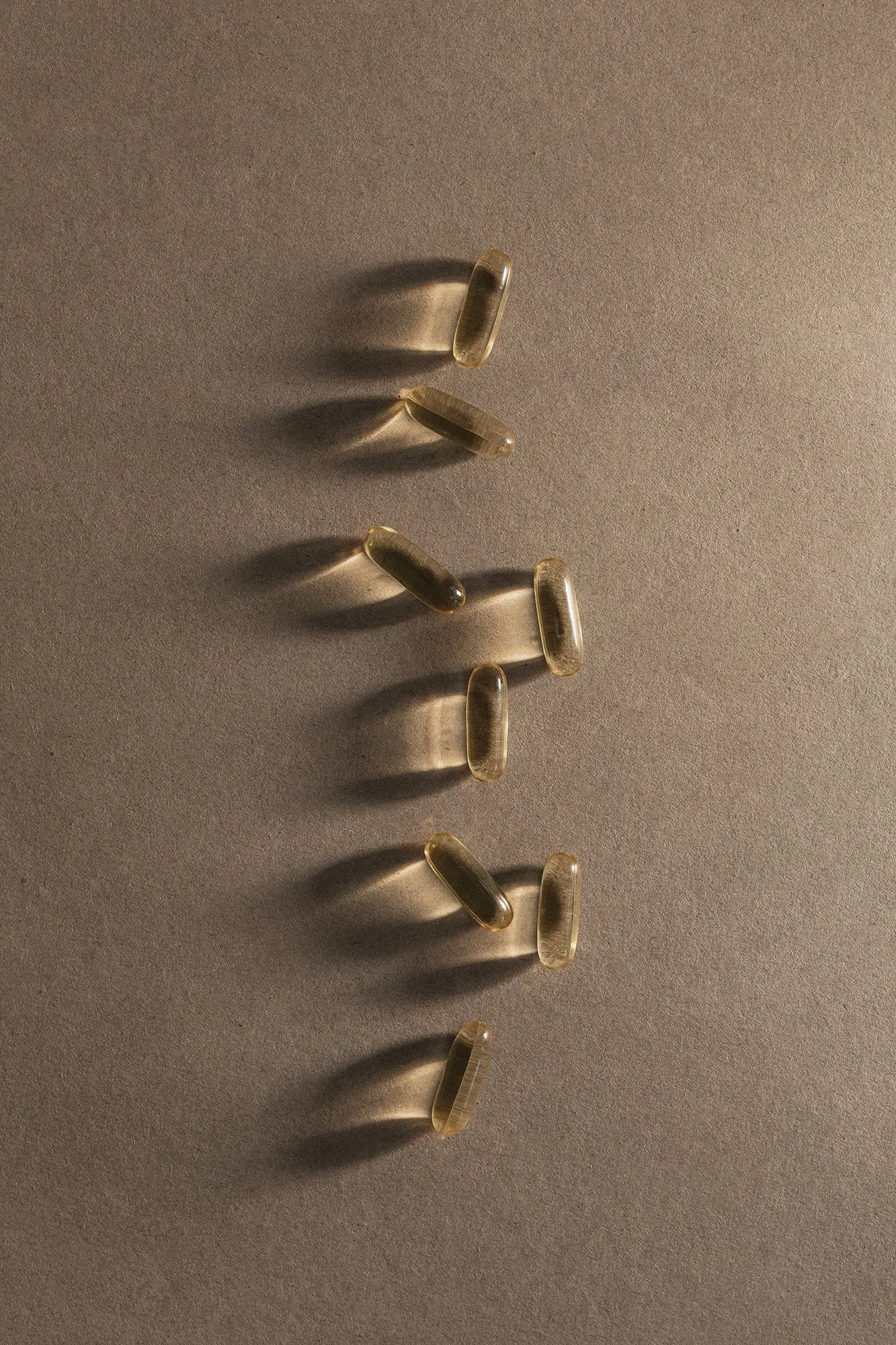 Multiple transparent gel capsules arranged on a light-colored surface with shadows cast underneath.