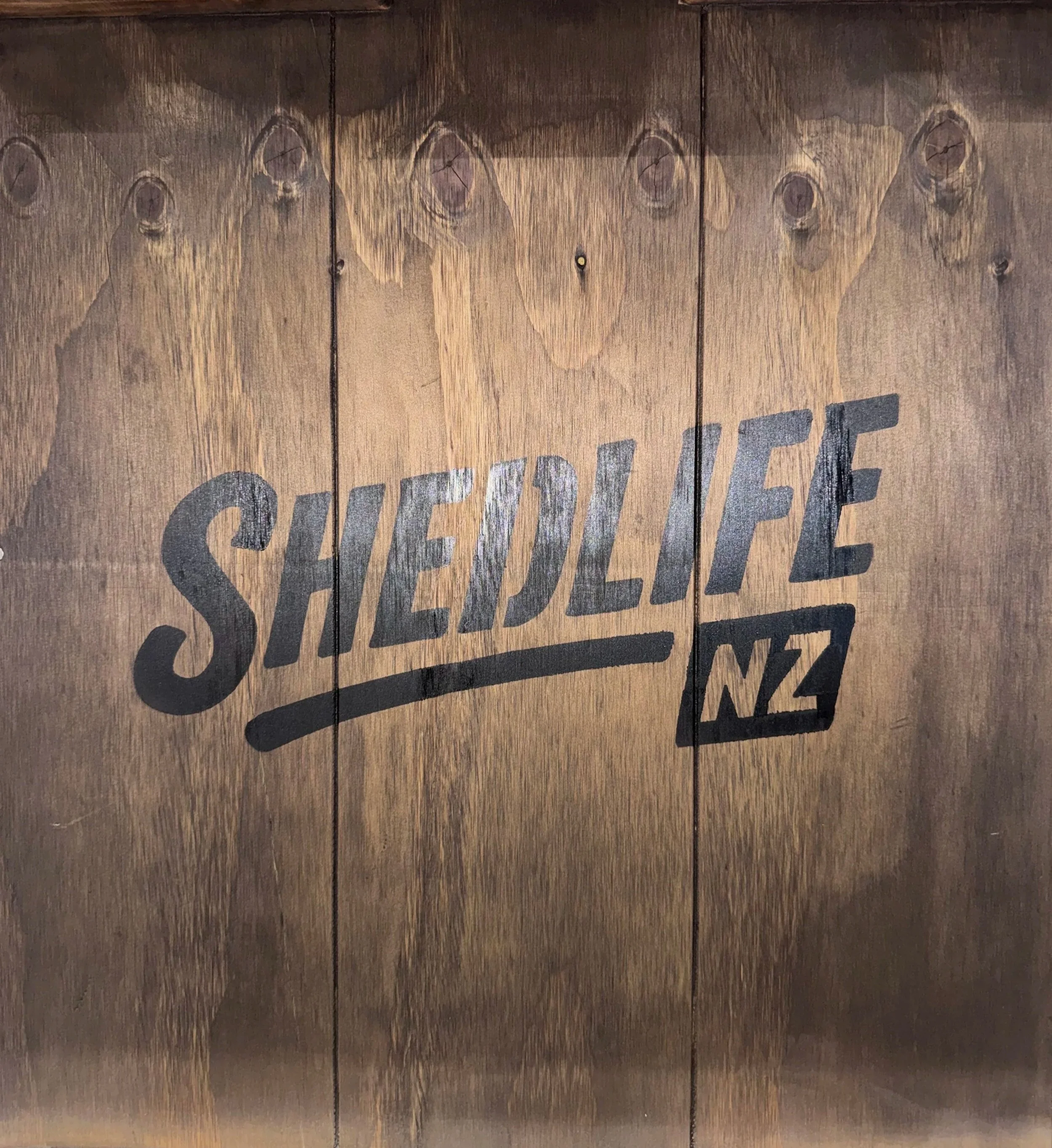 Wooden surface with the word "SHEDLIFENZ" painted on it.