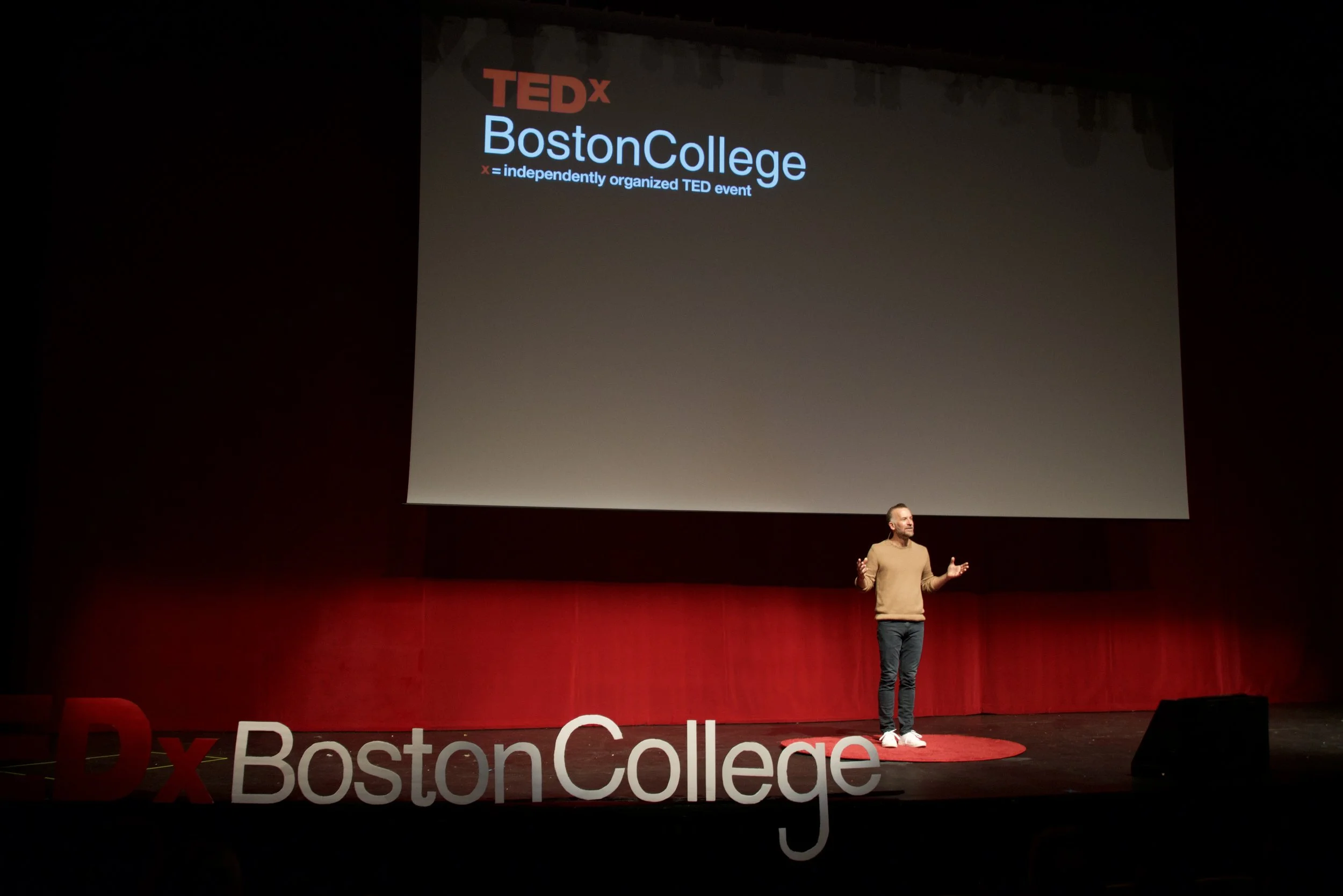 Adam Hill standing on stage at TEDx Boston College
