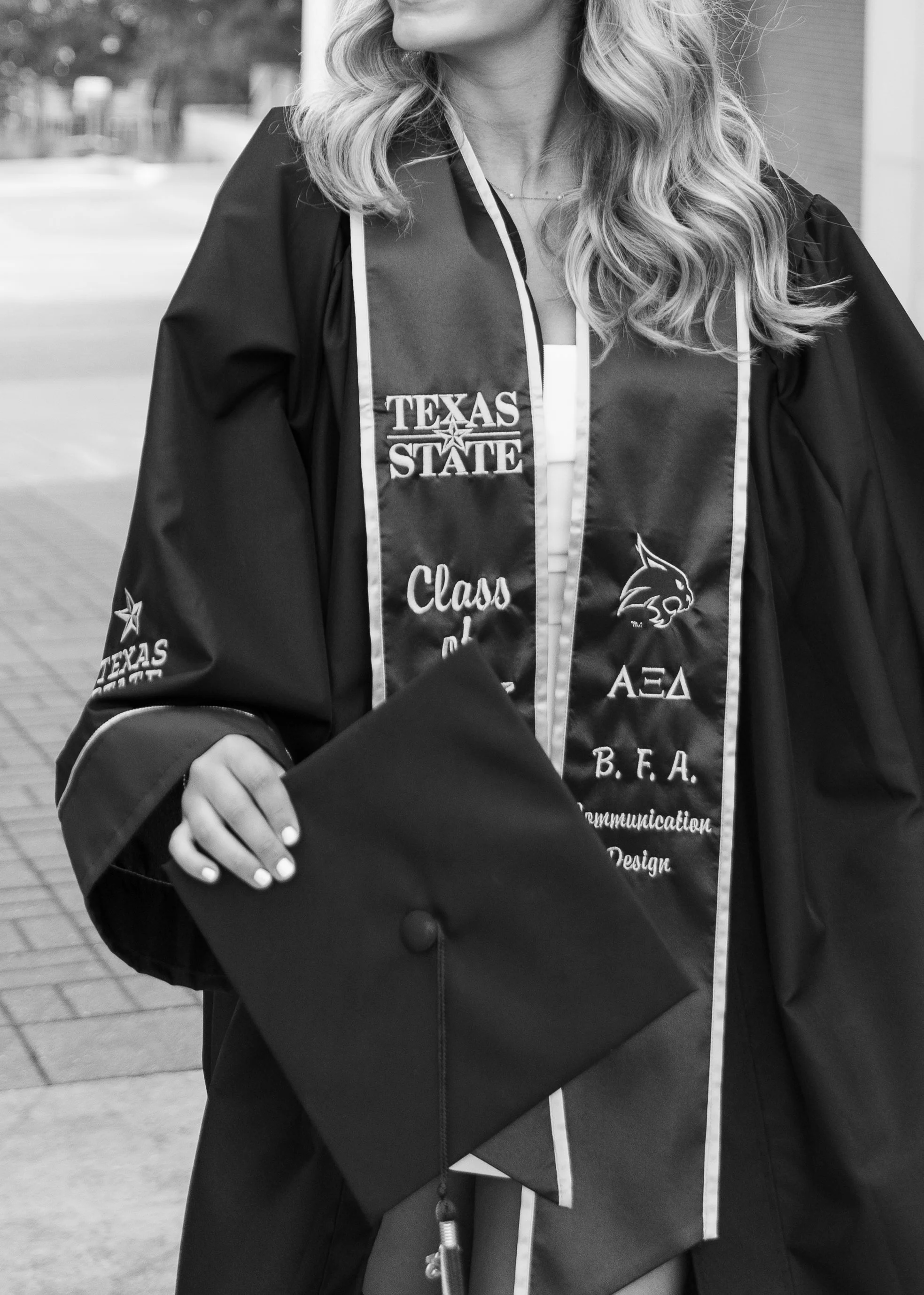 A woman in a graduation gown holding her cap.