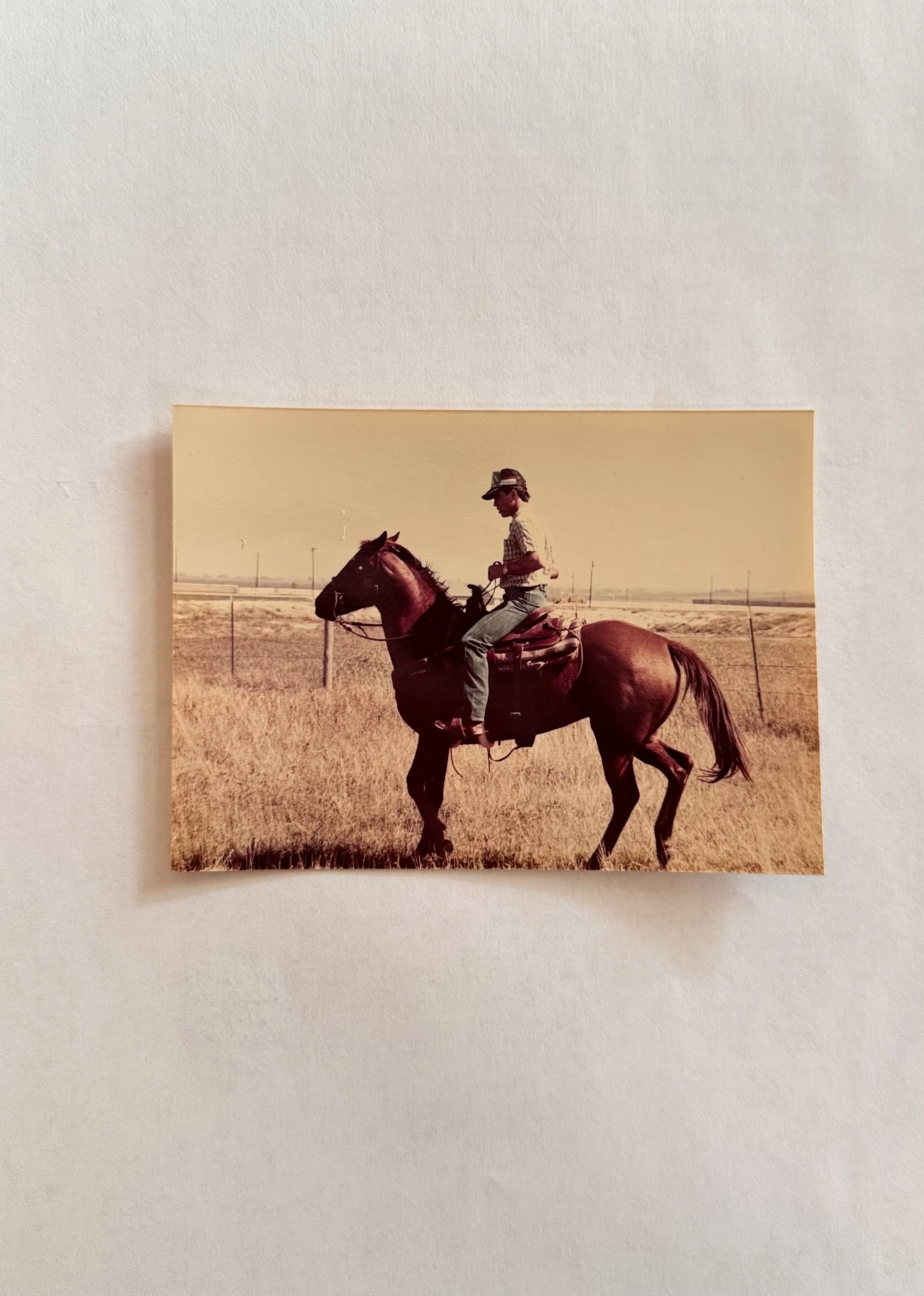 A man riding a horse in a flat, open field under a clear sky.