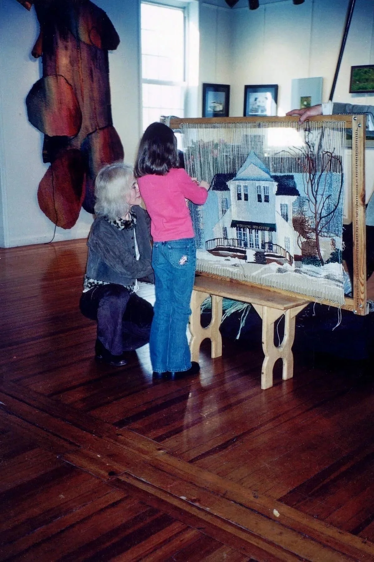 Nina share's the art of weaving hand dyed sisal fibers with a young visitor at Watchung Arts Center.  Nina designed a large textile piece depicting the historic building where the arts center celebrated 25 years in sessions and continues today.
