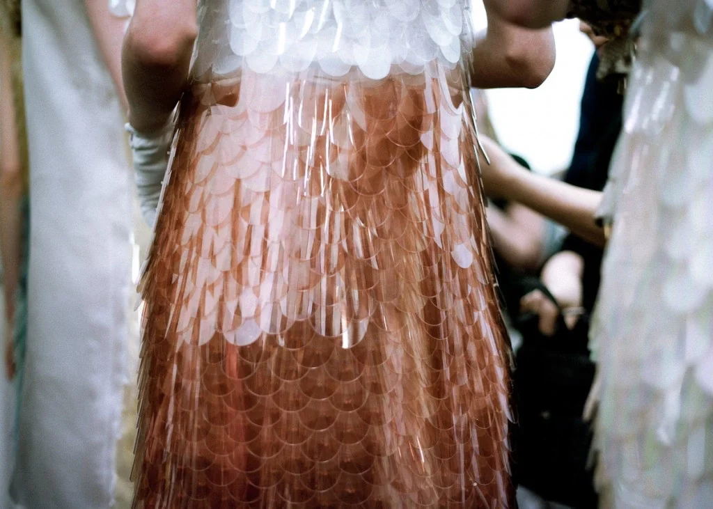 Close-up of a copper-colored dress with sequins resembling overlapping fish scales, worn by a person at a social event.